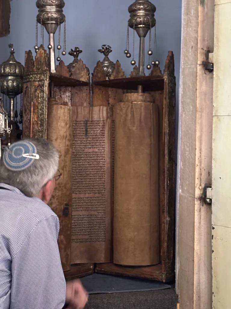 A photo of Rabbi Ron Segal in the beautiful Romaniote synagogue in Ioannina reading a 625 year old Torah